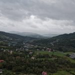 Cloudy sky over a green valley with scattered houses.
