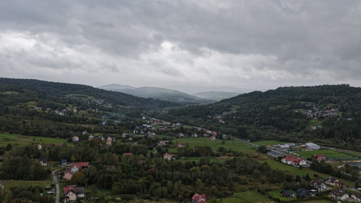 Cloudy sky over a green valley with scattered houses.