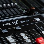 Detailed view of a professional audio mixer in a recording studio, featuring various knobs and sliders.